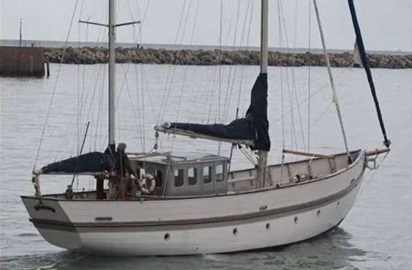 Photo of a smart white painted yacht with two masts and a small wheelhouse.